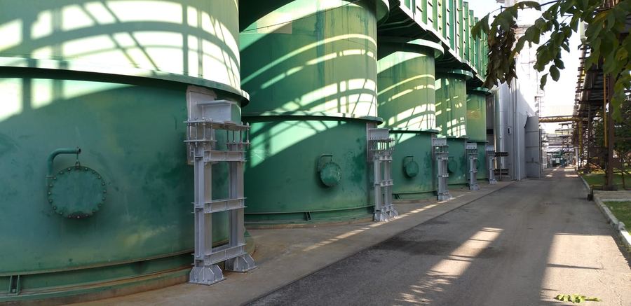 Fila di serbatoi di stoccaggio verdi appoggiati su strutture metalliche